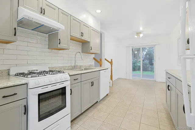a kitchen with granite countertop a stove sink and cabinets