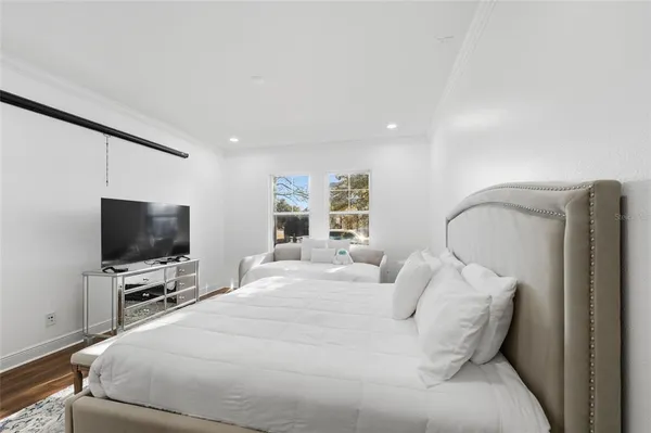 a bedroom with a bed a television and a large window