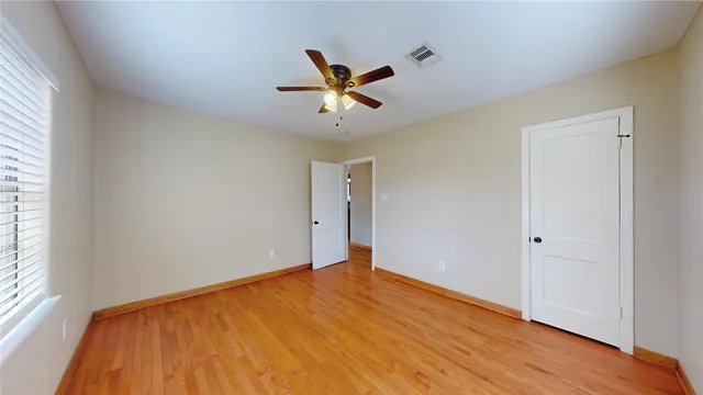 a view of empty room with wooden floor and fan