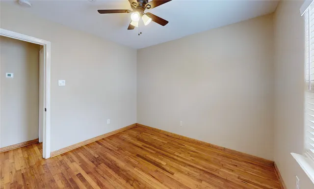 an empty room with a window and a ceiling fan