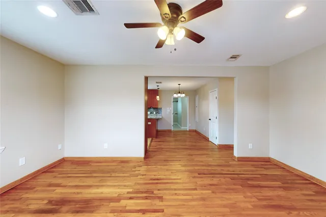 a view of a room with wooden floor and a ceiling fan