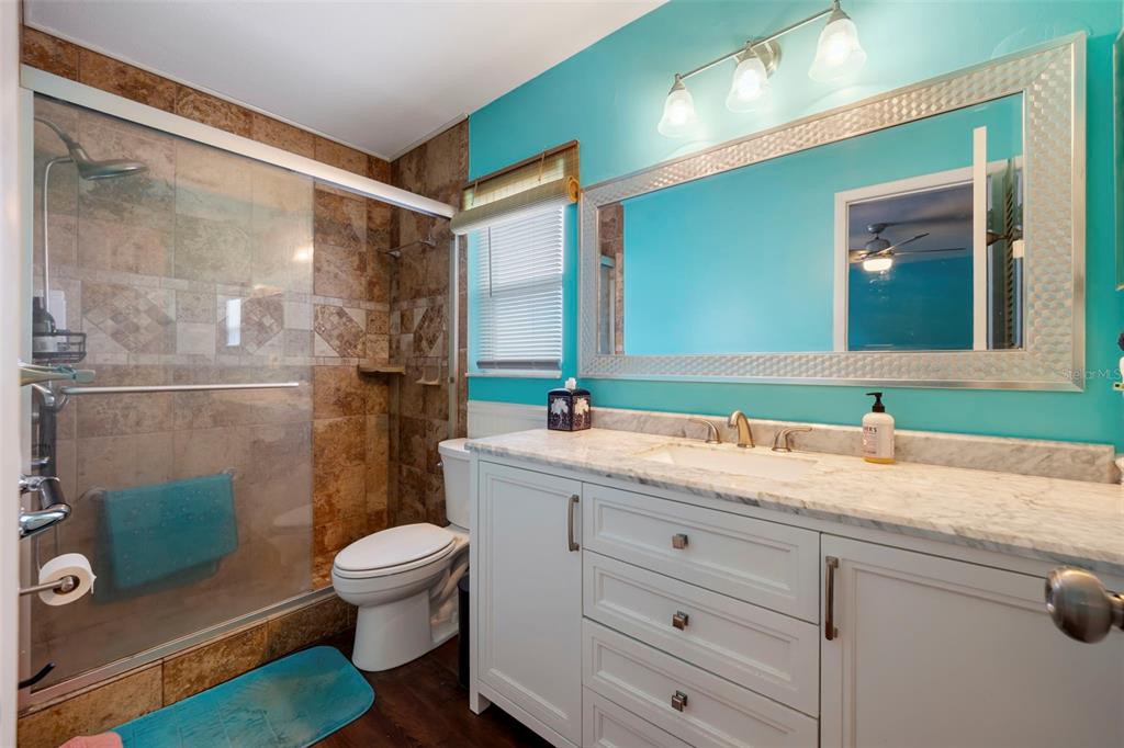 818 Eunice Drive Tarpon Springs, FL 34689 - Photo 18 of 59 a bathroom with a granite countertop sink toilet a mirror and shower