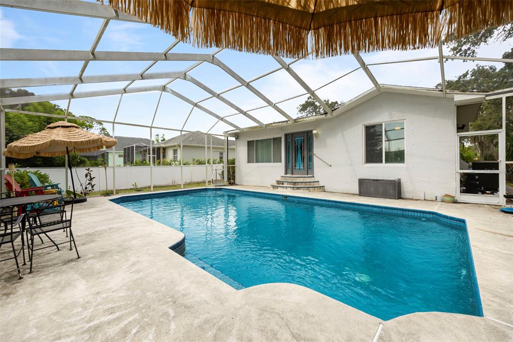 818 Eunice Drive Tarpon Springs, FL 34689 - Photo 30 of 59 a view of a patio with a table and chairs under an umbrella