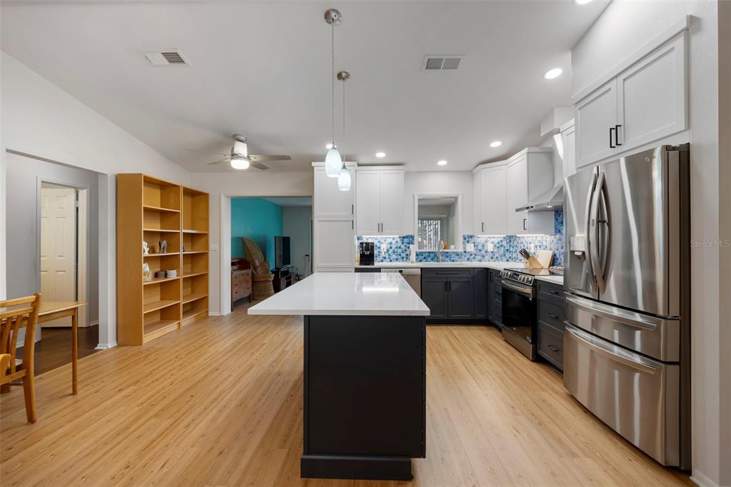 818 Eunice Drive Tarpon Springs, FL 34689 - Photo 9 of 59 a kitchen with stainless steel appliances kitchen island granite countertop a refrigerator a sink dishwasher and a stove with wooden floor