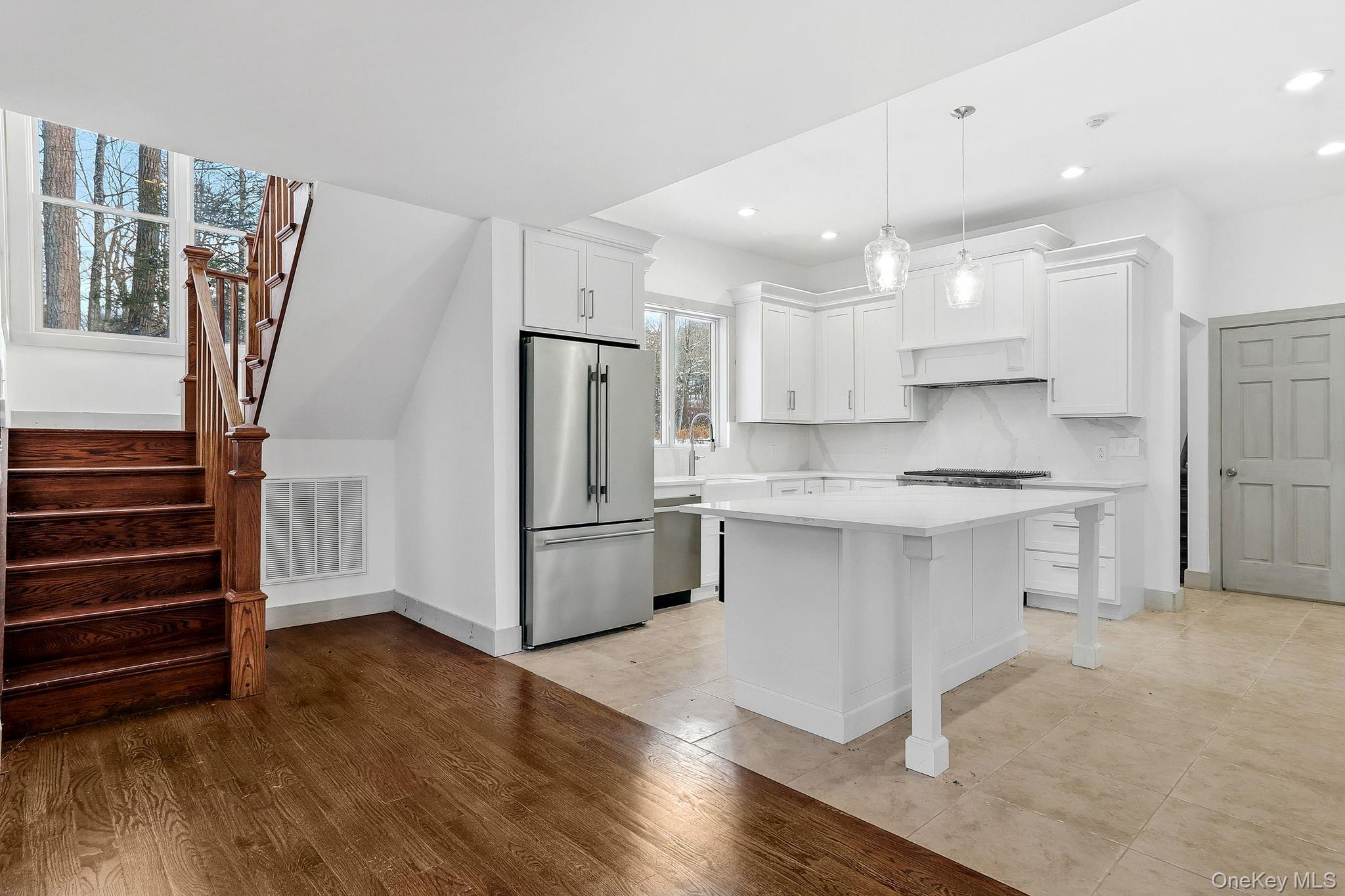 344 Schultz Hill Road Rhinebeck, NY 12572 - Photo 11 of 43 Kitchen featuring appliances with stainless steel finishes, light wood-style floors, white cabinets, decorative light fixtures, and a breakfast bar