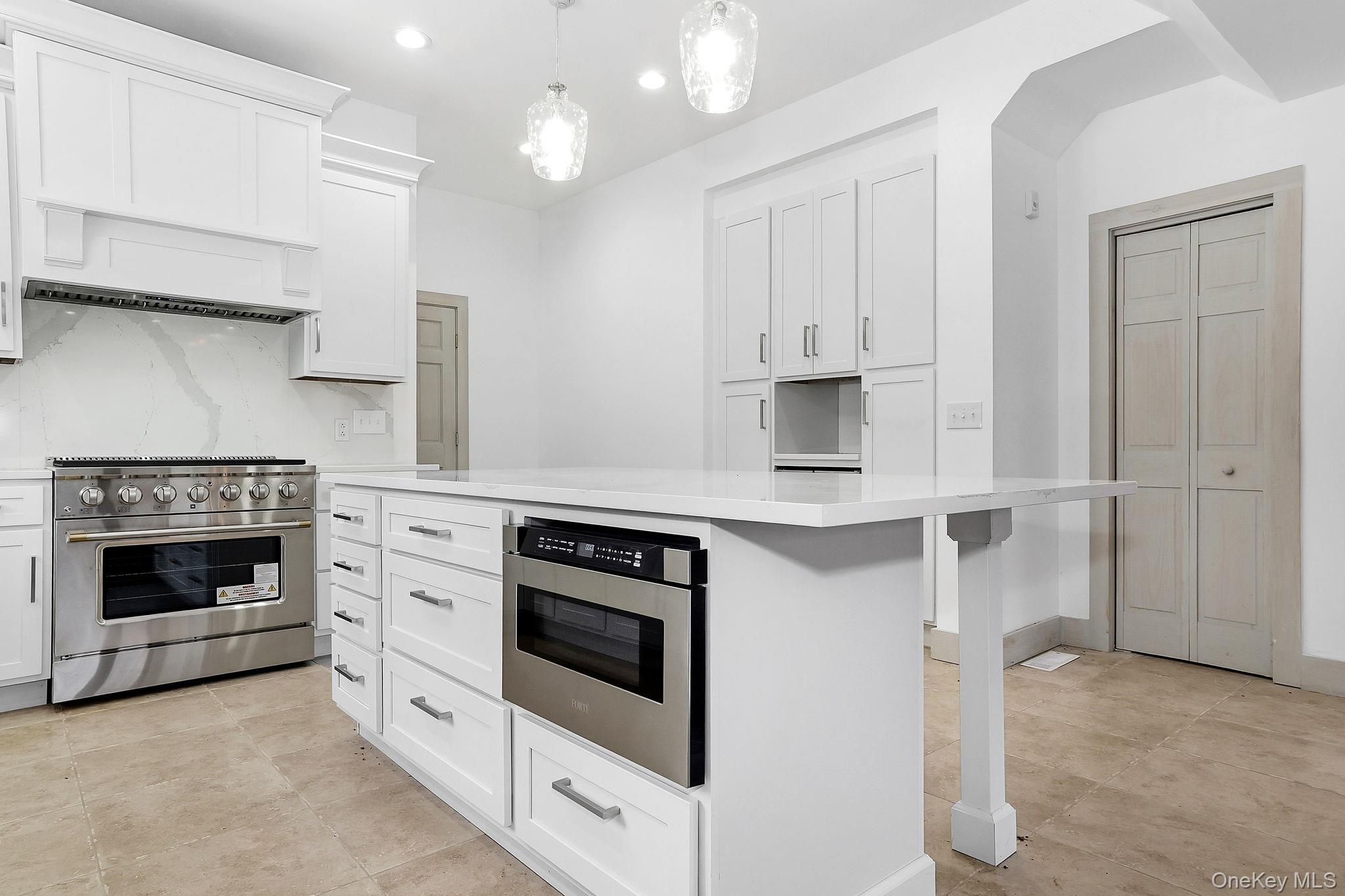 344 Schultz Hill Road Rhinebeck, NY 12572 - Photo 14 of 43 Kitchen with appliances with stainless steel finishes, white cabinetry, pendant lighting, a kitchen island, and light tile patterned floors