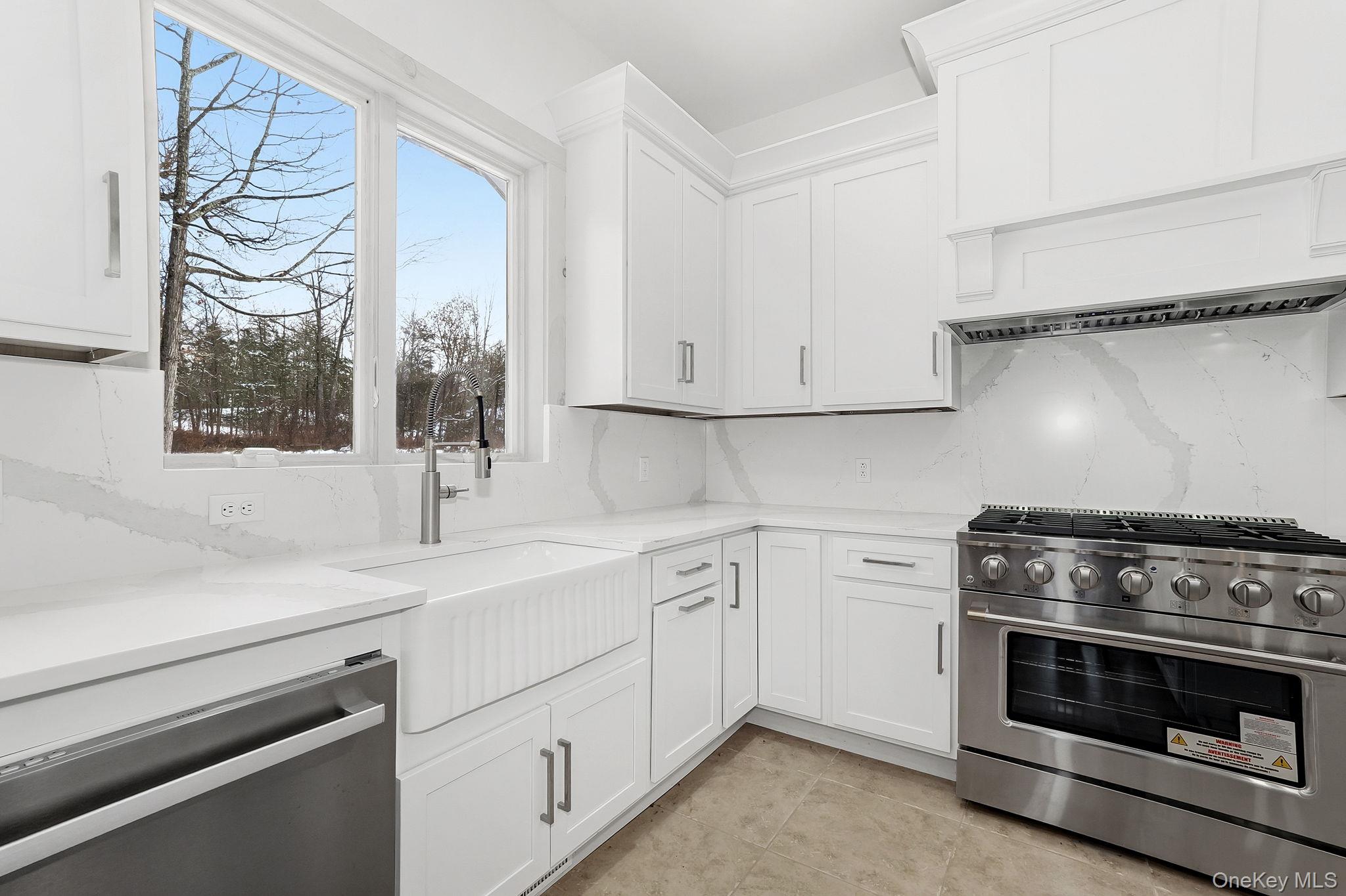344 Schultz Hill Road Rhinebeck, NY 12572 - Photo 15 of 43 Kitchen with stainless steel appliances, white cabinets, light stone countertops, exhaust hood, and light tile patterned floors