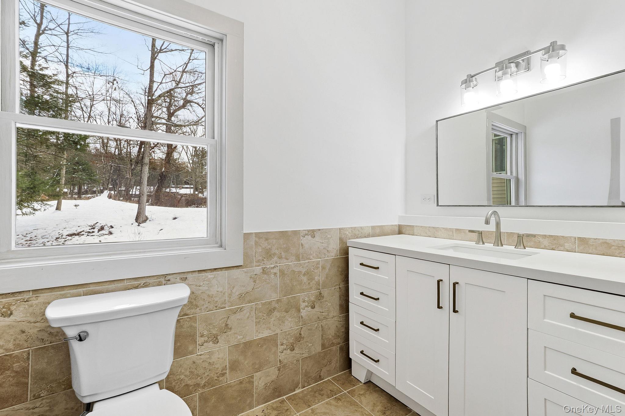 344 Schultz Hill Road Rhinebeck, NY 12572 - Photo 17 of 43 Bathroom with a wainscoted wall, vanity, tile walls, and light tile patterned floors