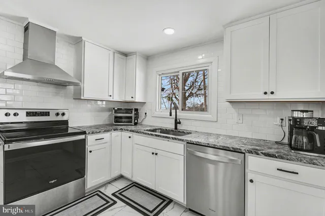 a kitchen with granite countertop white cabinets and stainless steel appliances