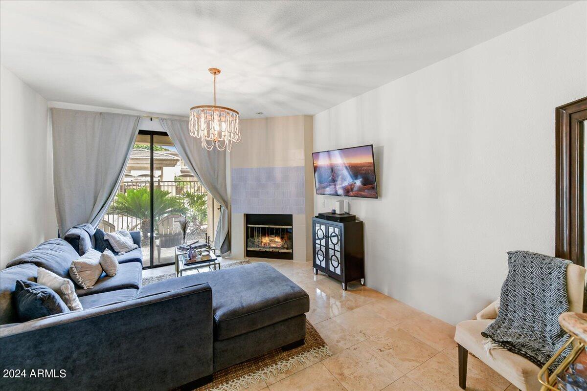 3235 East Camelback Road, Unit 109 Phoenix, AZ 85018 - Photo 4 of 20 a living room with furniture a fireplace and a chandelier