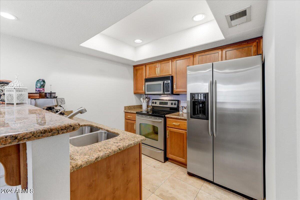 3235 East Camelback Road, Unit 109 Phoenix, AZ 85018 - Photo 9 of 20 a kitchen that has a refrigerator a sink and a stove with wooden floor