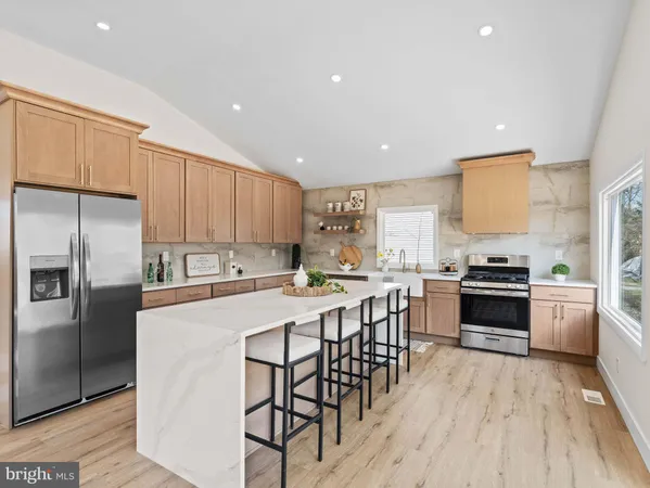 a kitchen with stainless steel appliances a stove a sink a refrigerator and white cabinets with wooden floor