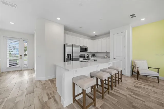 a kitchen with stainless steel appliances a table and chairs in it
