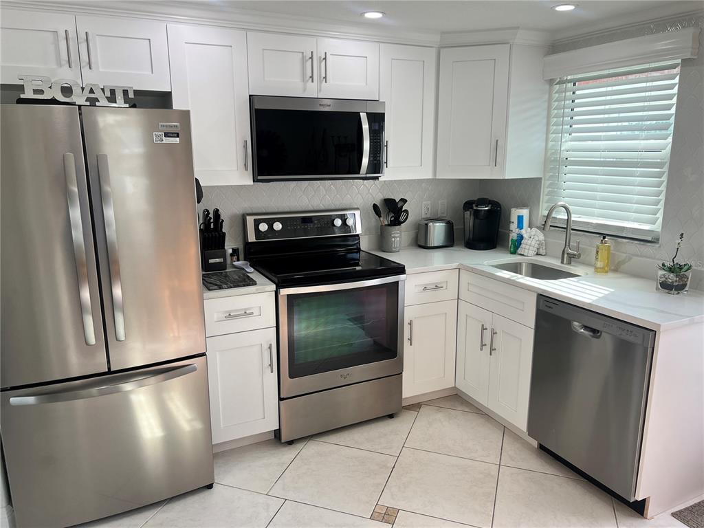 6154 Midnight Pass Road, Unit B16 Sarasota, FL 34242 - Photo 3 of 14 a kitchen with a refrigerator stove and microwave