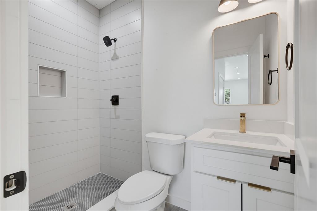 516 South O Connor Road Irving, TX 75060 - Photo 10 of 23 Bathroom featuring a walk-in shower with horizontal white tile, an integrated shower niche, and a contrasting penny tile floor