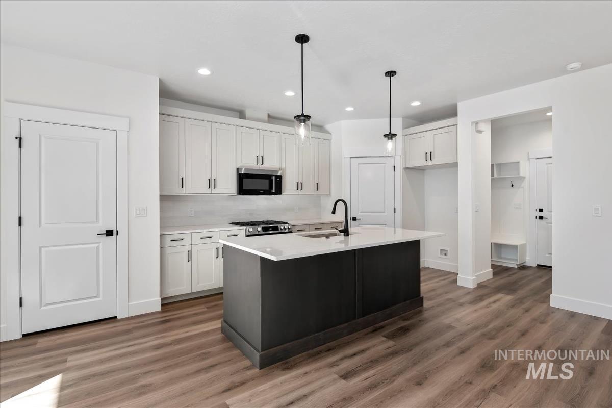 752 South Calhoun Lane Star, ID 83669 - Photo 7 of 45 Modern kitchen featuring a central island with a waterfall-edge countertop, matte black fixtures, and pendant lighting