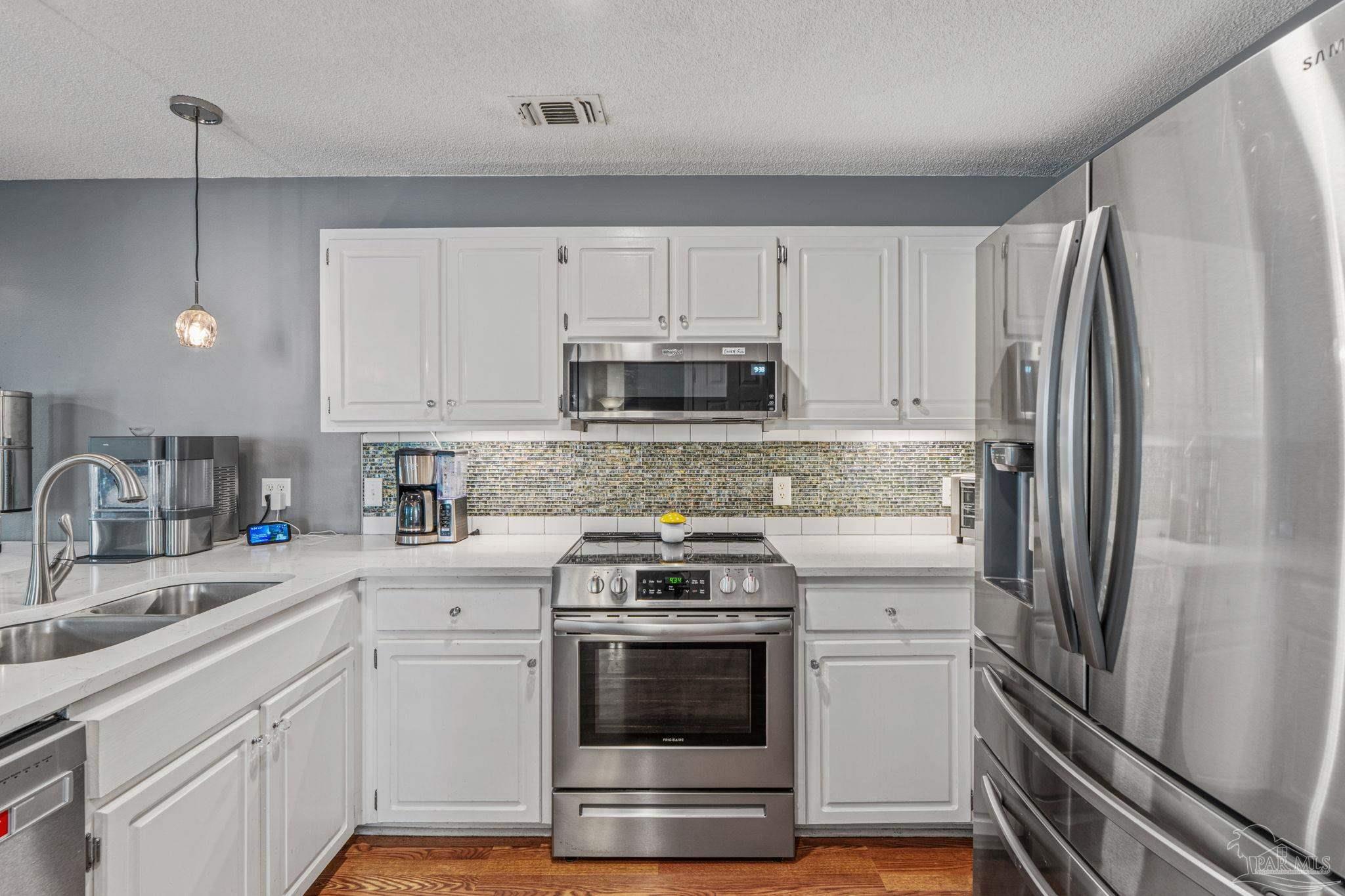 1739 Ivalea Circle Navarre, FL 32566 - Photo 18 of 46 a kitchen with white cabinets and stainless steel appliances
