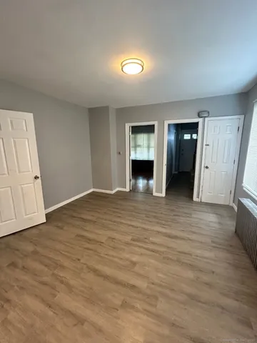 an empty room with wooden floor and bathroom