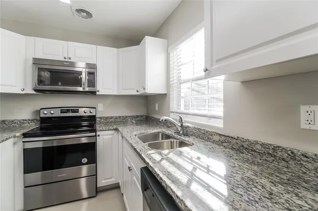a kitchen with granite countertop a stove sink and microwave