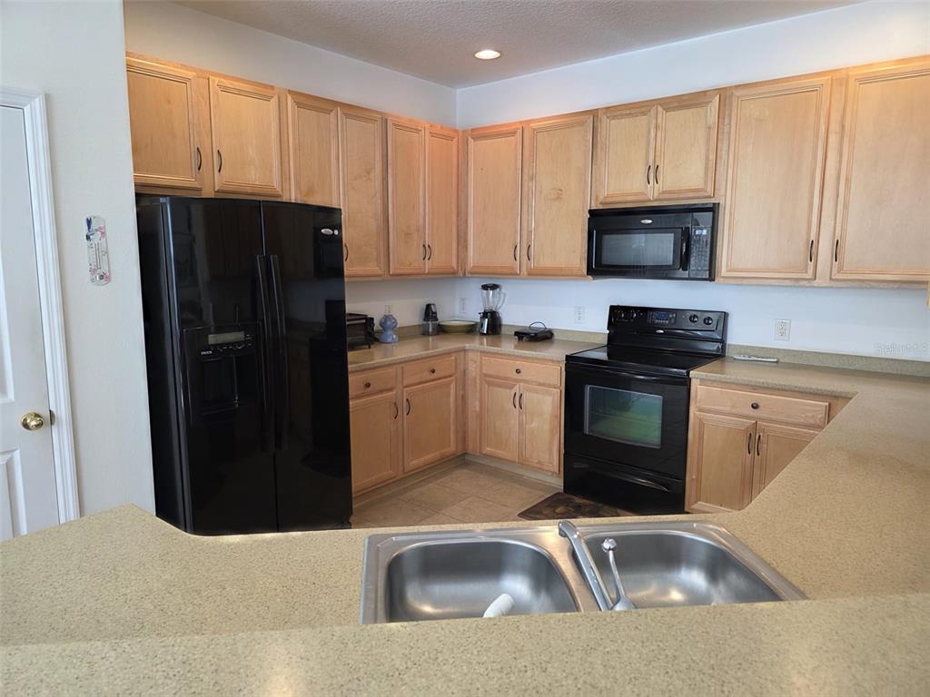 5160 Ambergris Loop Kissimmee, FL 34746 - Photo 9 of 38 a kitchen with a sink a refrigerator and cabinets