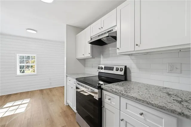 a kitchen with granite countertop wooden cabinets and a stove top oven