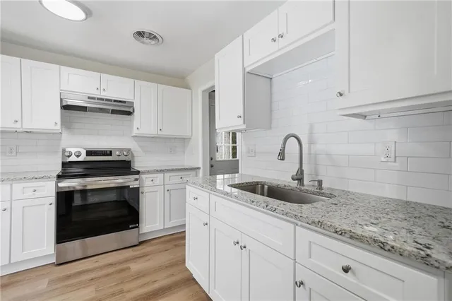 a kitchen with sink a stove and cabinets