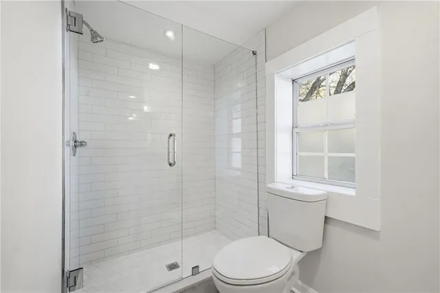 a white toilet sitting next to a shower