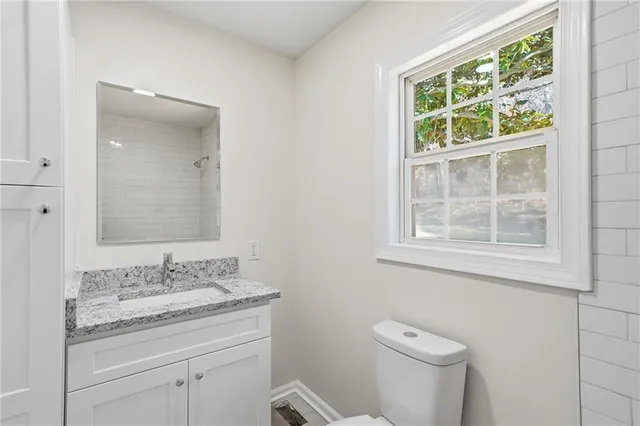 a bathroom with a granite countertop toilet a sink and a mirror