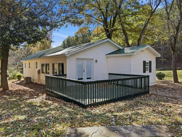 a view of a white house with a large window and wooden fence