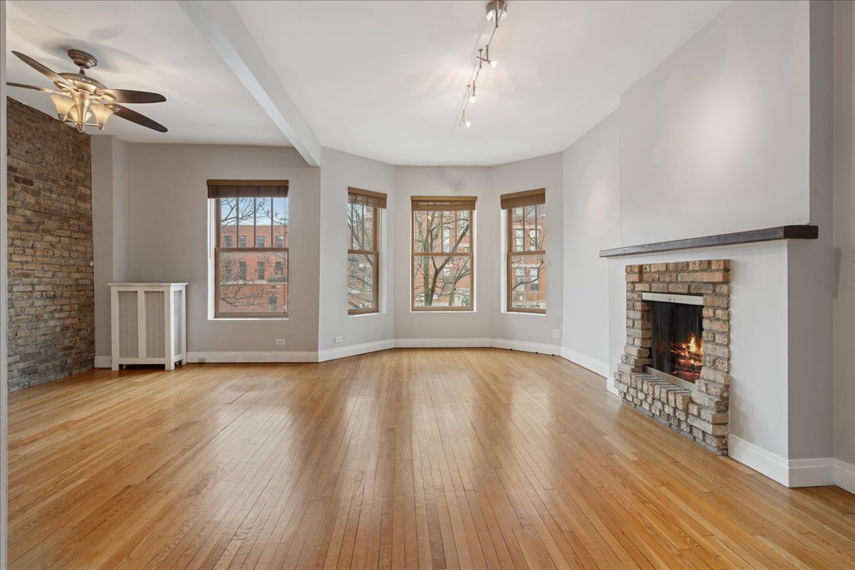 609 West Melrose Street, Unit 2 Chicago, IL 60657 - Photo 3 of 16 an empty room with wooden floor fireplace and windows