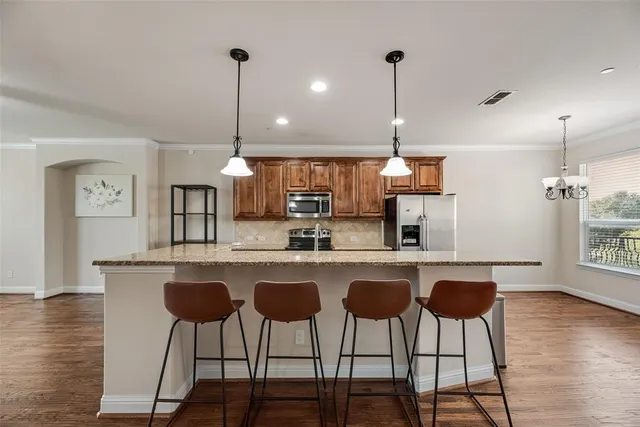 a kitchen with stainless steel appliances granite countertop a dining table chairs and white cabinets