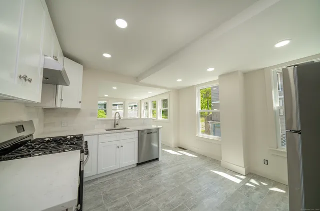 a large kitchen with stainless steel appliances granite countertop a refrigerator and a stove top oven