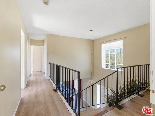 a view of a hallway with wooden floor and windows