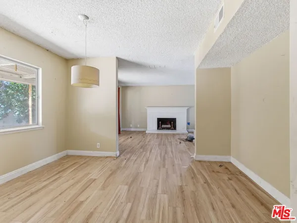 a view of empty room with wooden floor and fireplace