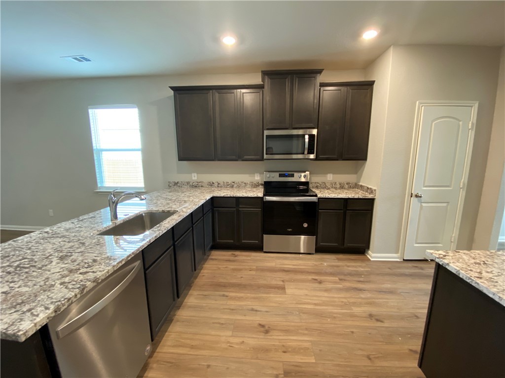 113 Declaration Lane Liberty Hill, TX 78642 - Photo 5 of 22 a kitchen with stainless steel appliances granite countertop a sink a stove top oven a refrigerator and dishwasher
