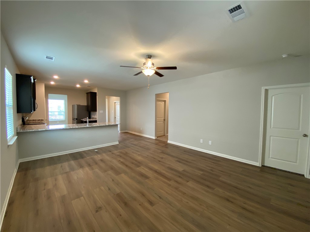 113 Declaration Lane Liberty Hill, TX 78642 - Photo 8 of 22 an empty room with wooden floor a kitchen view and a chandelier fan
