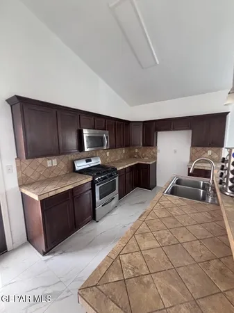 a living room with stainless steel appliances kitchen island granite countertop a sink stove and white cabinets