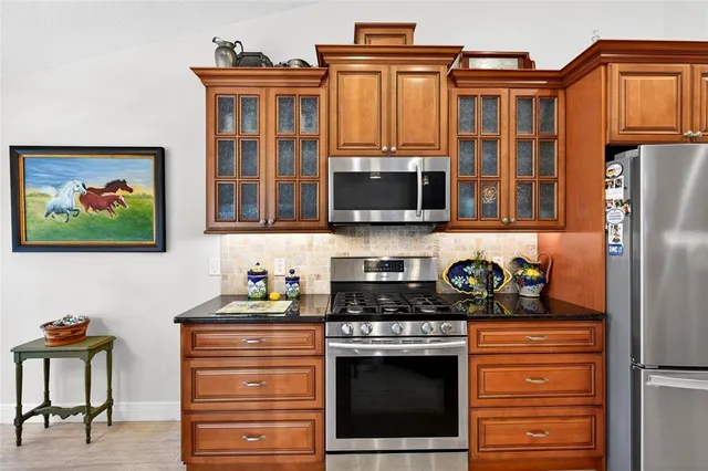 a kitchen with stainless steel appliances granite countertop a stove top oven a sink dishwasher and cabinets with wooden floor