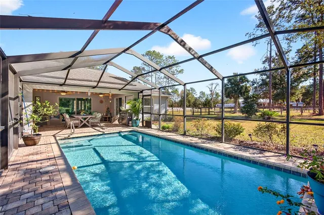 a backyard of a house with table and chairs under an umbrella