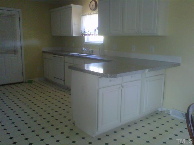 26 Chic Ennis Road Coats, NC 27521 - Photo 2 of 6 Kitchen is spacious with beautiful white cabinets. Nice overhang on bar is great for entertaining. Dining area has view of covered back deck.