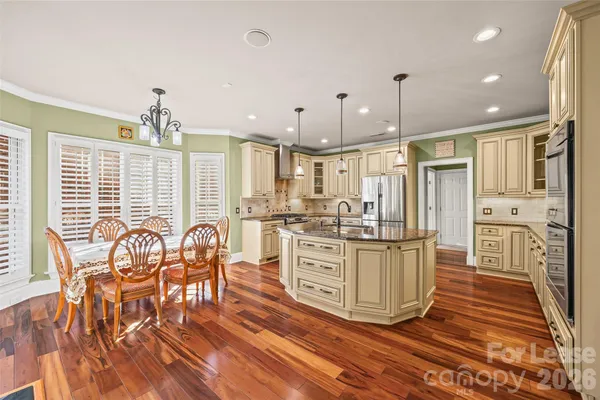a kitchen with stainless steel appliances kitchen island granite countertop a dining table chairs and granite counter tops