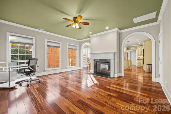a view of a livingroom with a fireplace a ceiling fan and wooden floor