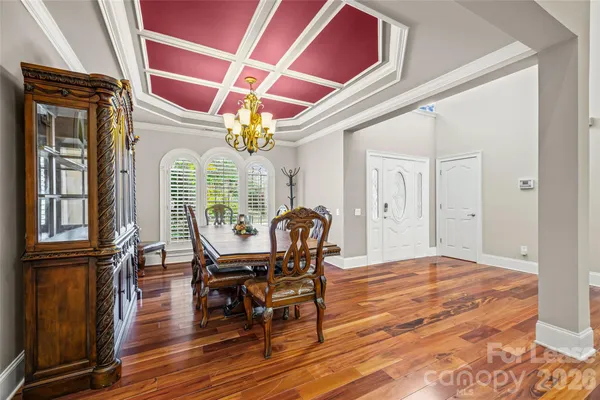 a dining room with wooden floor a glass table and chairs