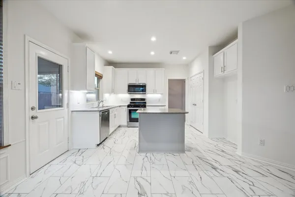 a kitchen with stainless steel appliances kitchen island sink refrigerator and cabinets