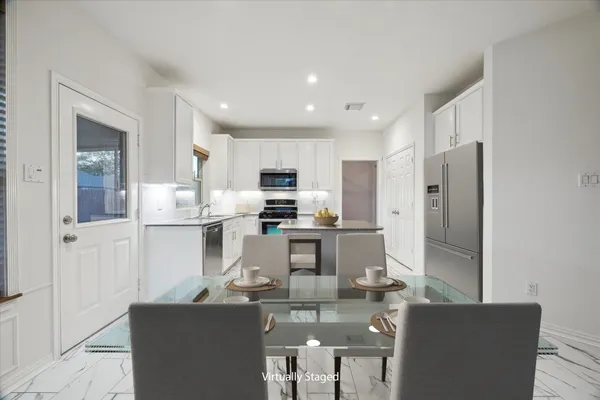 a kitchen with stainless steel appliances kitchen island granite countertop a refrigerator a stove a sink a dining table and chairs