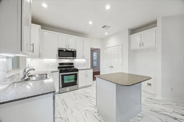 a kitchen with granite countertop a sink stove and refrigerator