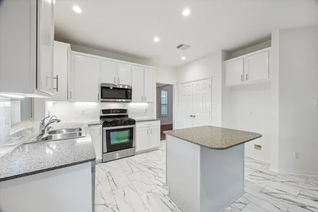 a kitchen with granite countertop a sink stove and refrigerator