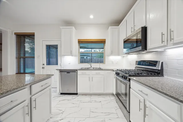 a kitchen with stainless steel appliances granite countertop a stove a sink and a microwave