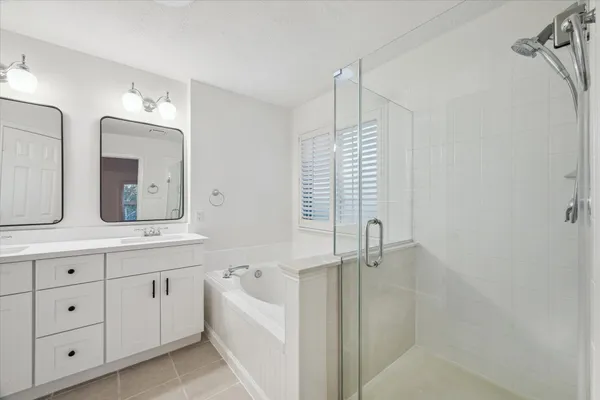 a bathroom with a double vanity sink a mirror and a bathtub