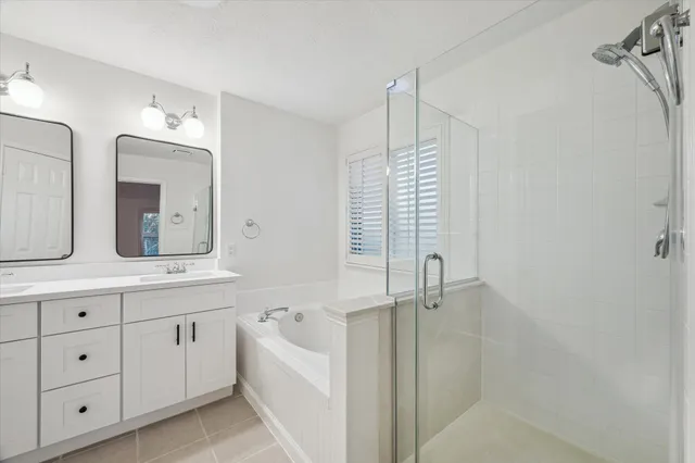 a bathroom with a double vanity sink a mirror and a bathtub